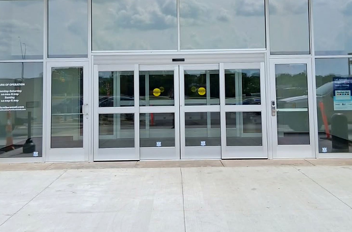 A full-height glass storefront with a bi-parting automatic sliding entrance and swing doors on each side