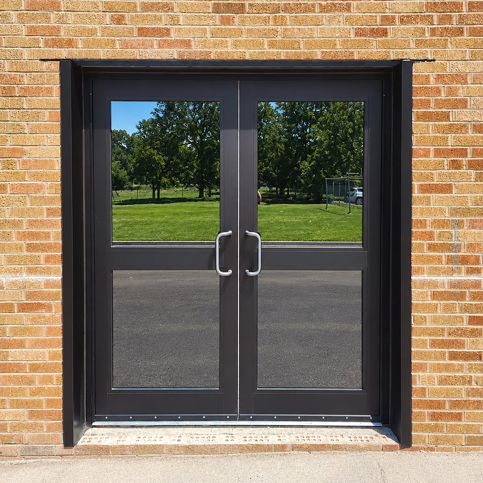 After: new dark aluminum double doors set into a fresh opening in the brick wall