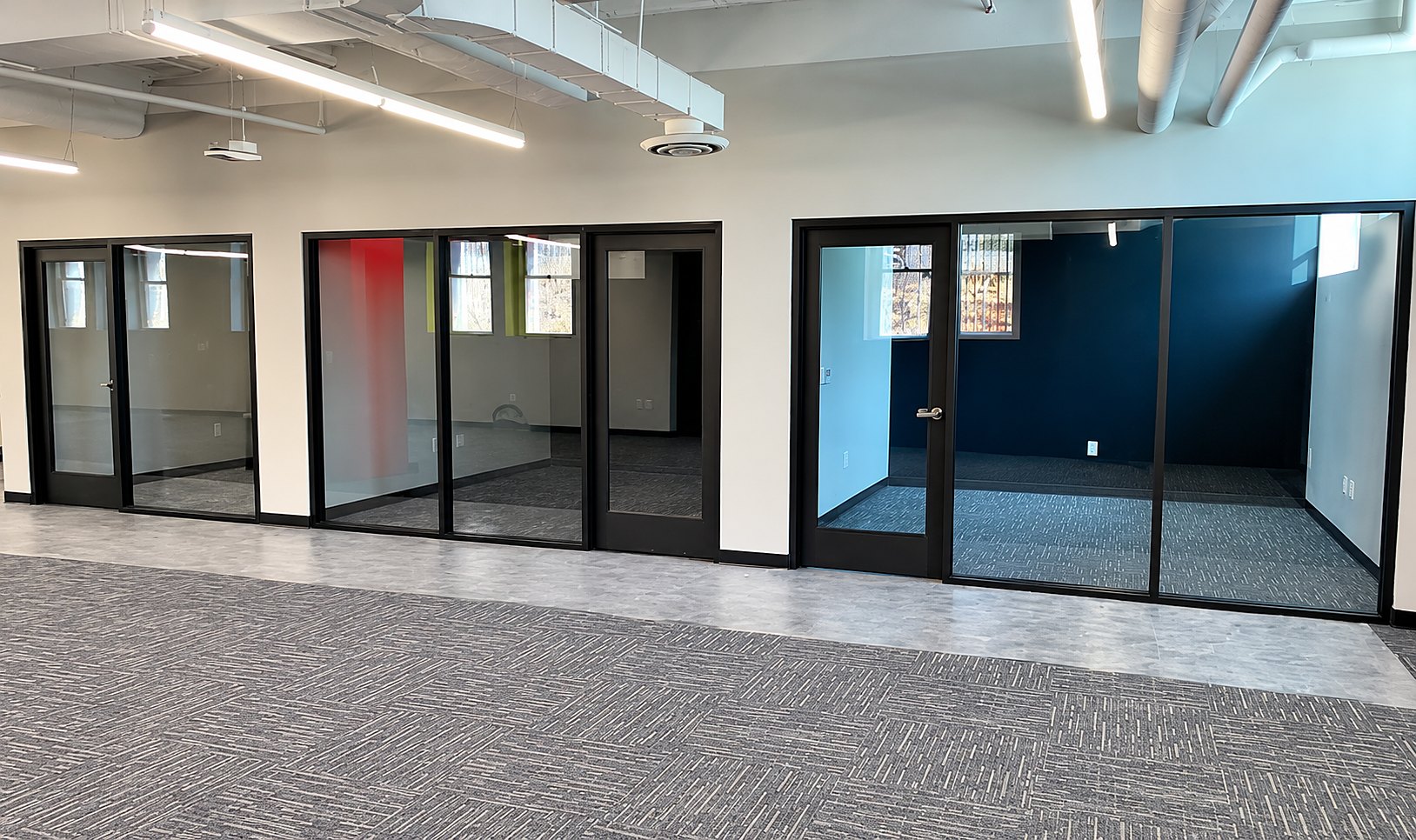 A row of black-framed interior glass office fronts and doors in a newly finished office